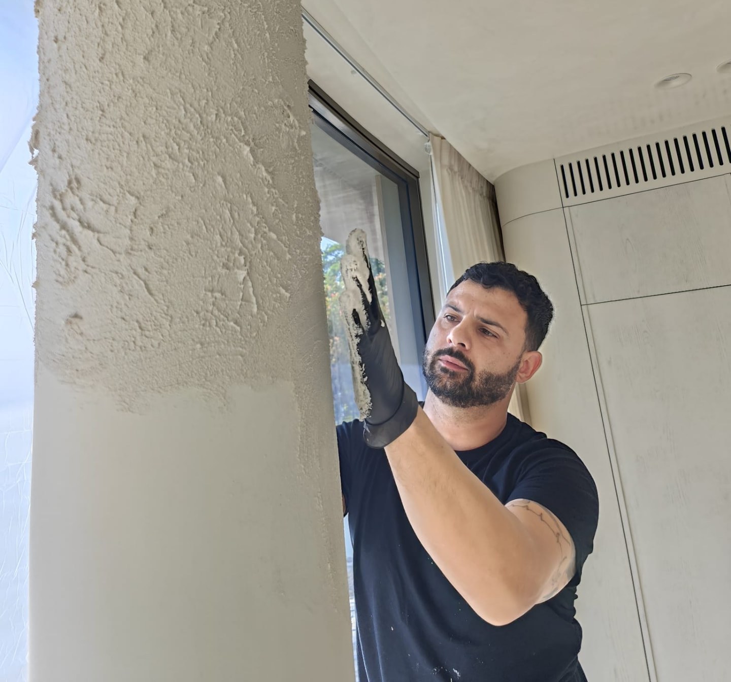 Giovanni Dori hand-applying a textured plaster finish to a column